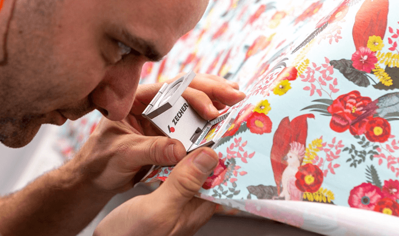 A Design Group employee inspects the print of a sheet of gift wrap up close.